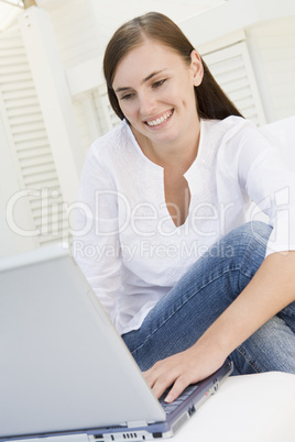 Woman on patio using laptop and smiling