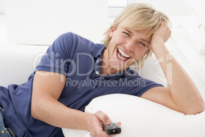 Man in living room holding remote control laughing