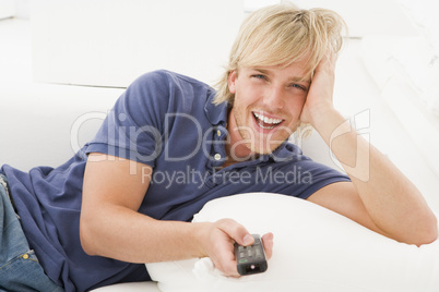 Man in living room holding remote control laughing