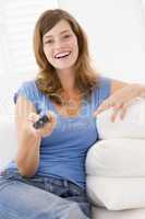 Woman in living room with remote control smiling