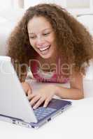 Woman lying in bed with laptop smiling