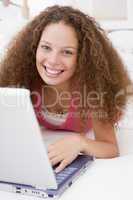 Woman lying in bed with laptop smiling