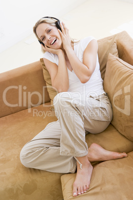 Woman in living room listening to headphones smiling