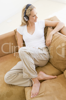 Woman in living room listening to headphones smiling