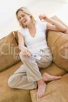 Woman in living room holding remote control smiling