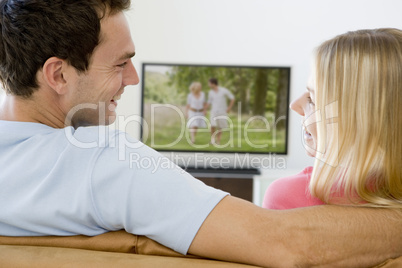 Couple in living room watching television smiling