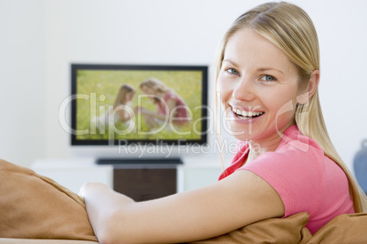 Woman in living room watching television smiling