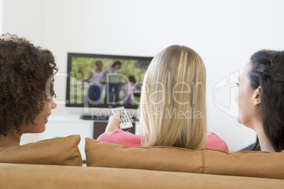 Three women in living room watching television