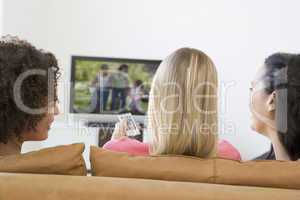 Three women in living room watching television