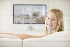 Woman in living room watching television smiling