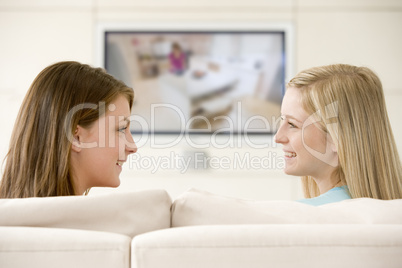 Two women in living room watching television smiling