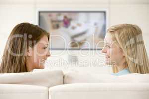 Two women in living room watching television smiling