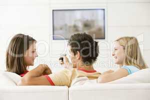 Three friends in living room watching television smiling