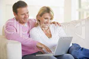 Couple in living room using laptop and smiling