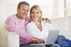 Couple in living room using laptop and smiling