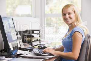 Woman in home office using computer and smiling