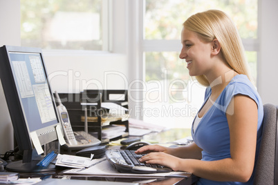 Woman in home office using computer and smiling