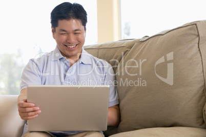 Man in living room using laptop and smiling