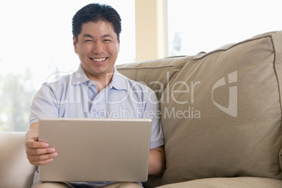 Man in living room using laptop and smiling