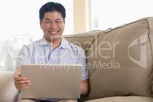 Man in living room using laptop and smiling