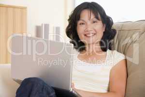 Woman in living room using laptop and smiling