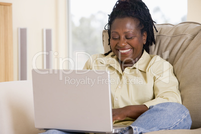 Woman in living room using laptop and smiling