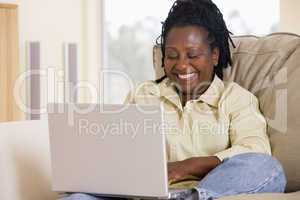 Woman in living room using laptop and smiling