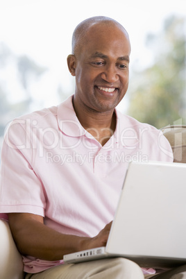 Man in living room using laptop and smiling