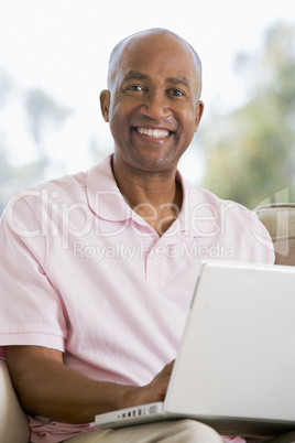 Man in living room using laptop and smiling