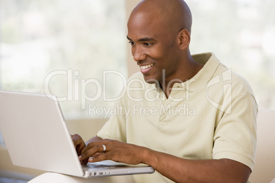 Man in living room using laptop and smiling