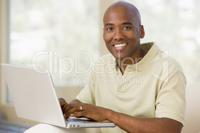 Man in living room using laptop and smiling