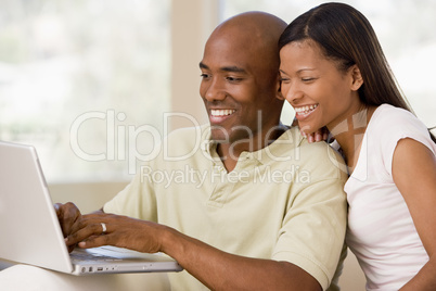 Couple in living room using laptop and smiling