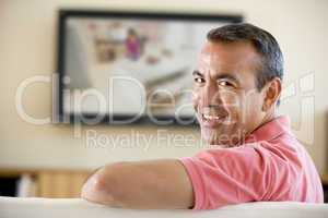 Man in living room watching television smiling