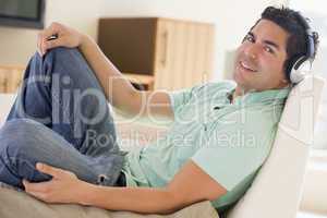 Man in living room listening to headphones smiling