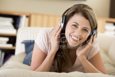 Woman in living room listening to headphones smiling