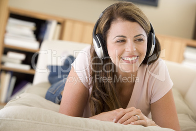 Woman in living room listening to headphones smiling