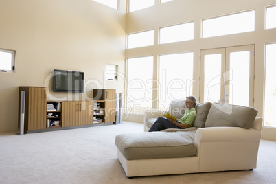 Man reading book in living room smiling