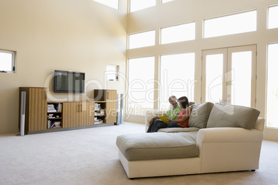 Couple reading book in living room smiling