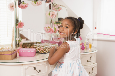 Young girl sitting at mirror in bedroom smiling