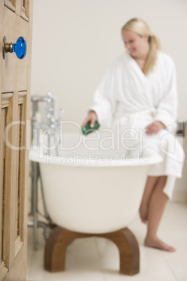 Woman in bathroom putting bubble bath in bathtub