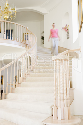 Woman coming down staircase in luxurious home