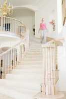 Woman coming down staircase in luxurious home