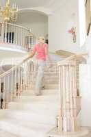 Woman going up staircase in luxurious home