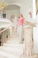 Woman coming down staircase in luxurious home