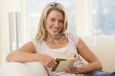 Woman in living room reading book smiling