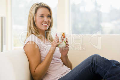 Woman in living room with coffee smiling