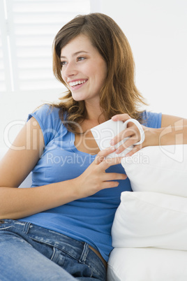 Woman in living room with coffee smiling