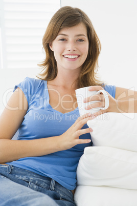 Woman in living room with coffee smiling