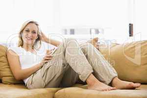 Woman in living room listening to MP3 player smiling