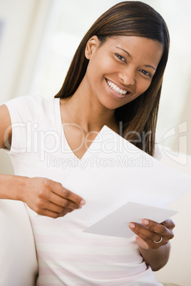 Woman in living room reading papers smiling